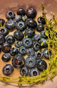 Closeup of pickled blueberries with thyme